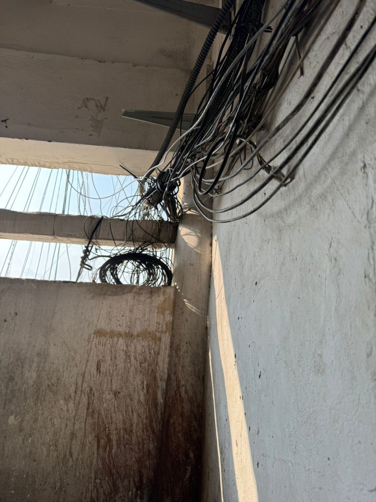 Exterior light-well with hanging cables and water stains