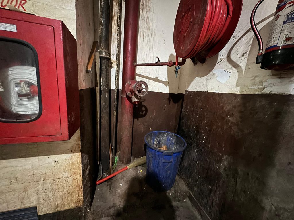 Fire hose reel corner cluttered by bucket/tools