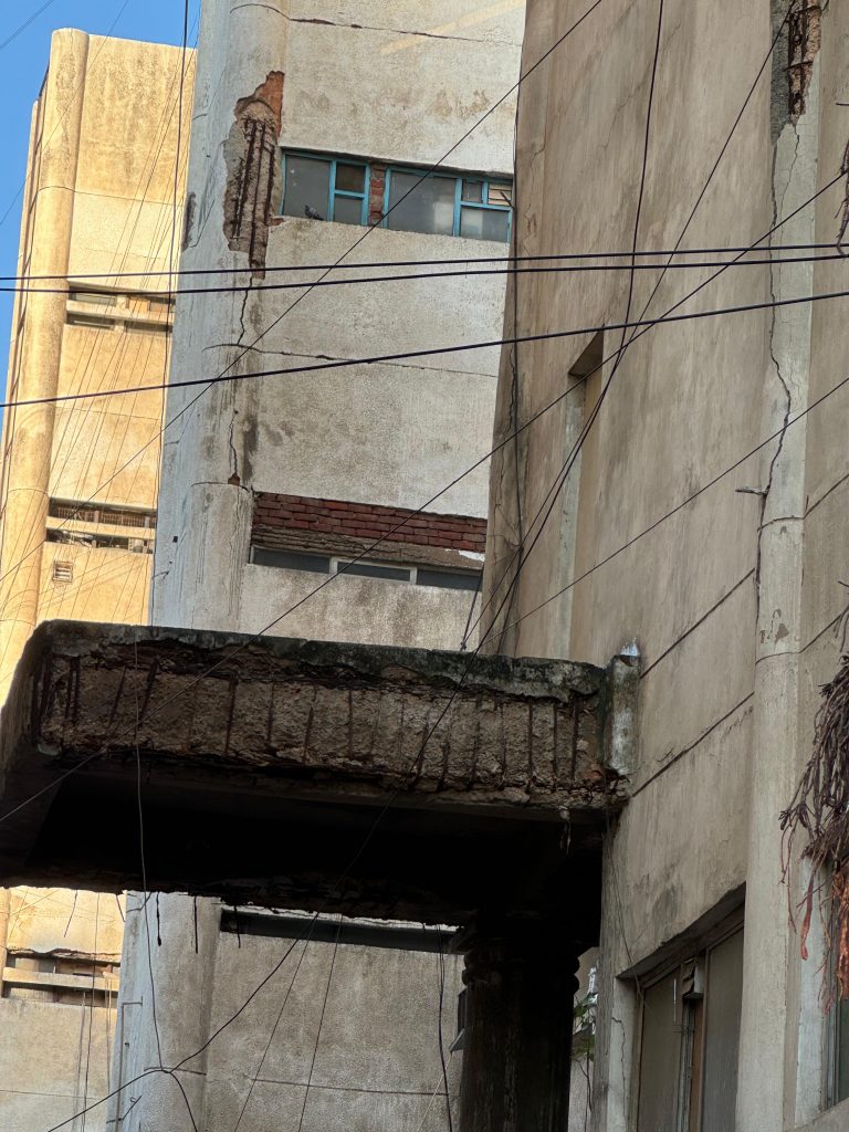 Angle view highlighting deep vertical crack running the height of the wall adjacent to the damaged slab.